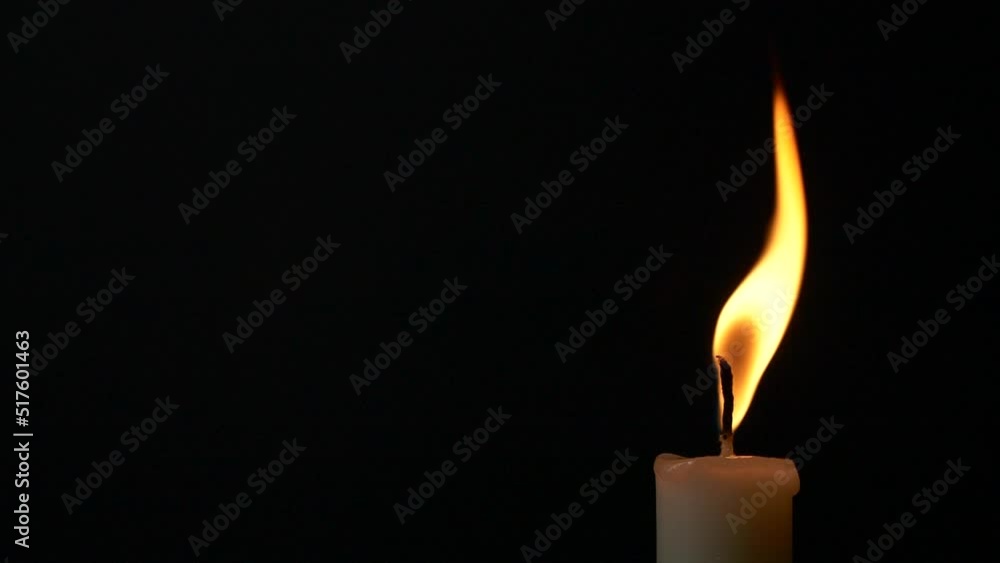 Slow motion closeup burning single candle flame isolated on black background Slow motion closeup burning single candle flame isolated on black background