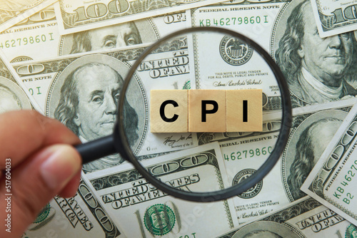 CPI, consumer price index symbol. hand holding magnifying glass investigating wooden block with words CPI, consumer price index on dollar bills. Business and CPI, consumer price index concept. photo