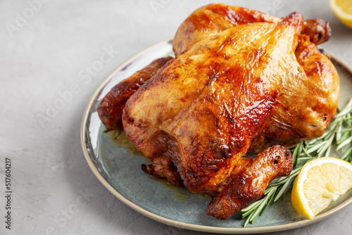 Homemade Lemon and Herb Rotisserie Chicken on a Plate on a gray background, side view. photo