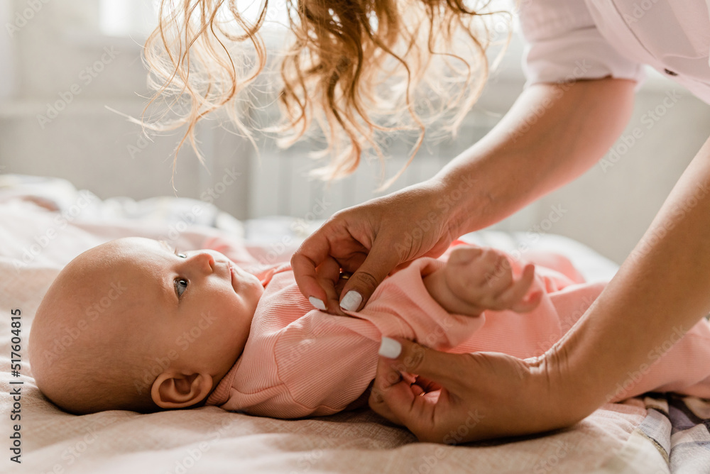 Mom with her baby newborn infant kid child at home take care in the bedroom put on clothes. Woman family women's health and maternity Mom with her baby newborn infant kid child at home take care in the bedroom put on clothes. Woman family women's health and maternity