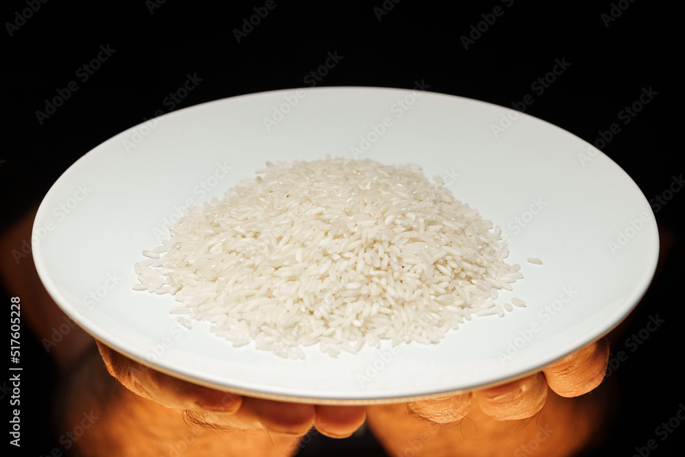 Hands holding a heap of dry rice grain on black background Hands holding a heap of dry rice grain on black background