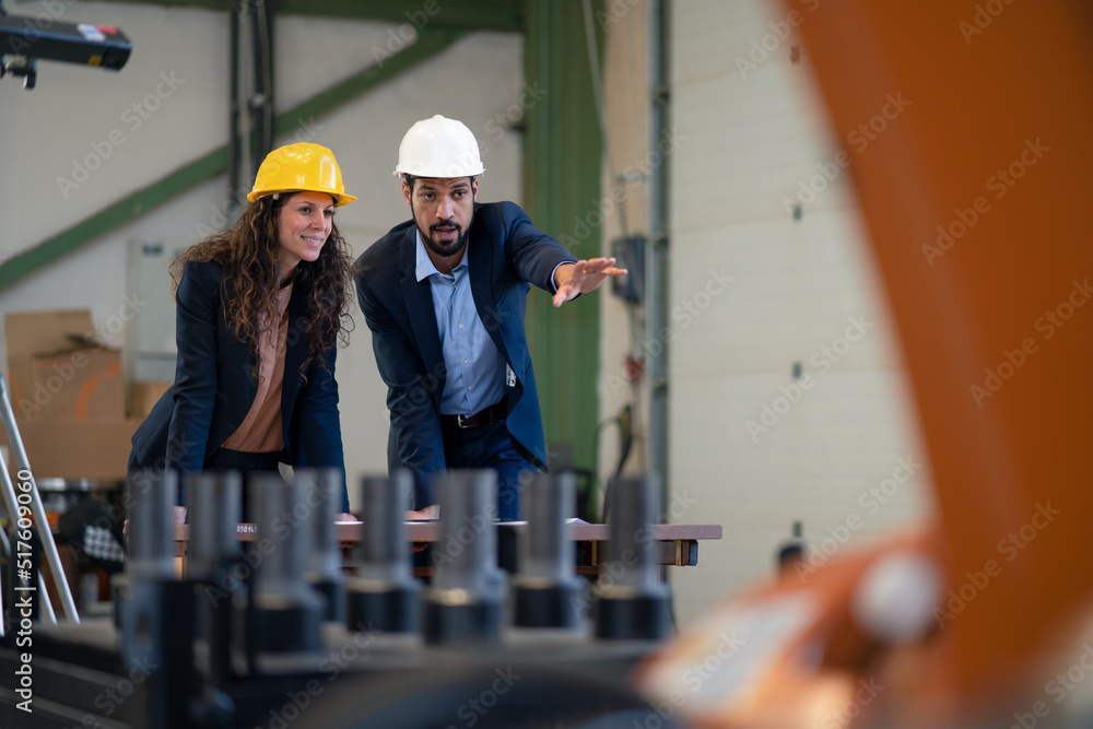 Chief engineer and project manager in modern industrial factory with robot arms talking and planning optimization of production. Chief engineer and project manager in modern industrial factory with robot arms talking and planning optimization of production.