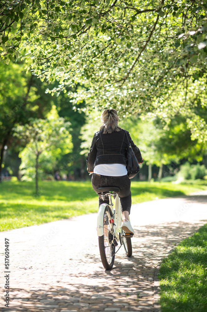 Fototapeta premium A woman in black jacket on a bike