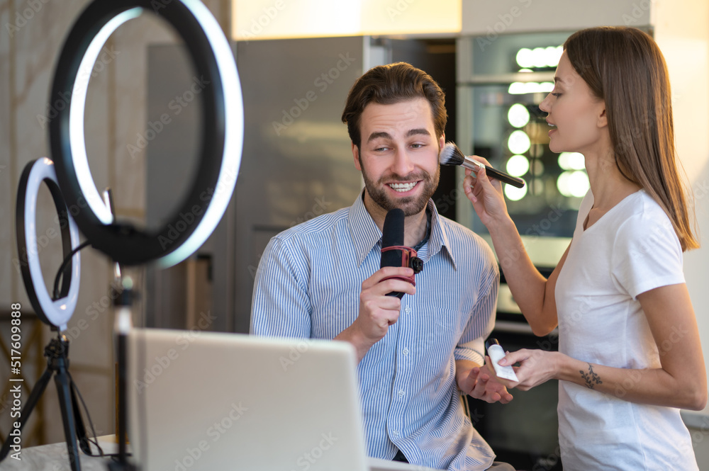 Female stylist doing make up to a journalist before broadcasting