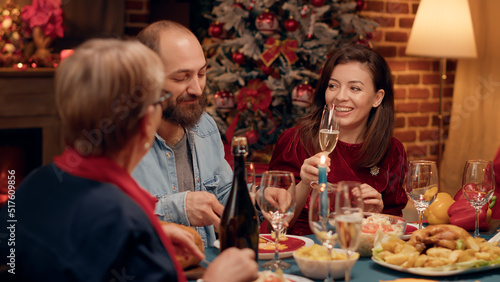 Happy people talking to each other while enjoying Christmas dinner at home. Festive joyful family members celebrating winter holiday while eating traditional home cooked food and chatting.