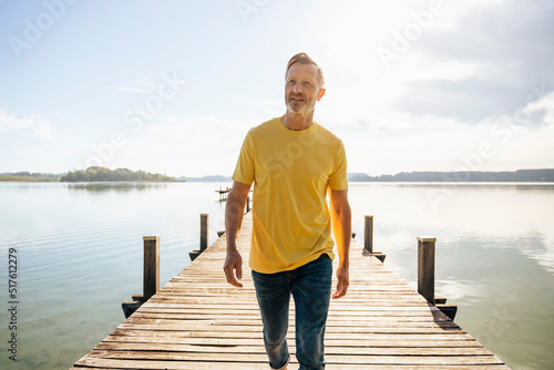 Mature man walking on pier at lake photo