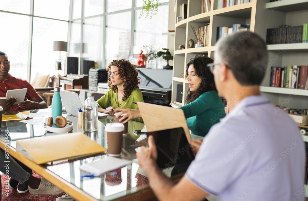 Mature businessman with colleagues sitting at desk in office Mature businessman with colleagues sitting at desk in office