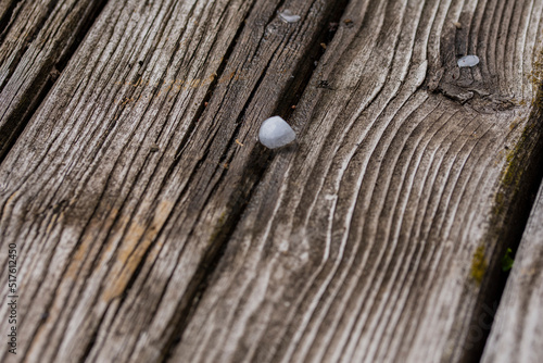 Small balls of hail, ice and hailstones from the sky on an old wooden table on a sunny day. Summer.