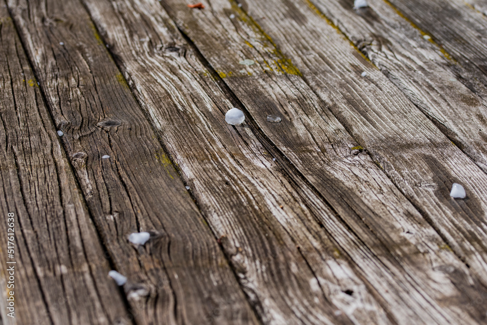 Obraz premium Small balls of hail, ice and hailstones from the sky on an old wooden table on a sunny day. Summer.