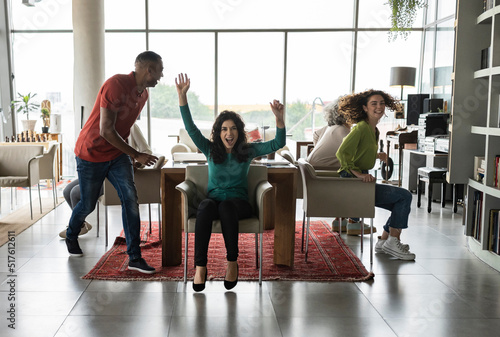 Cheerful business colleagues playing musical chairs in office