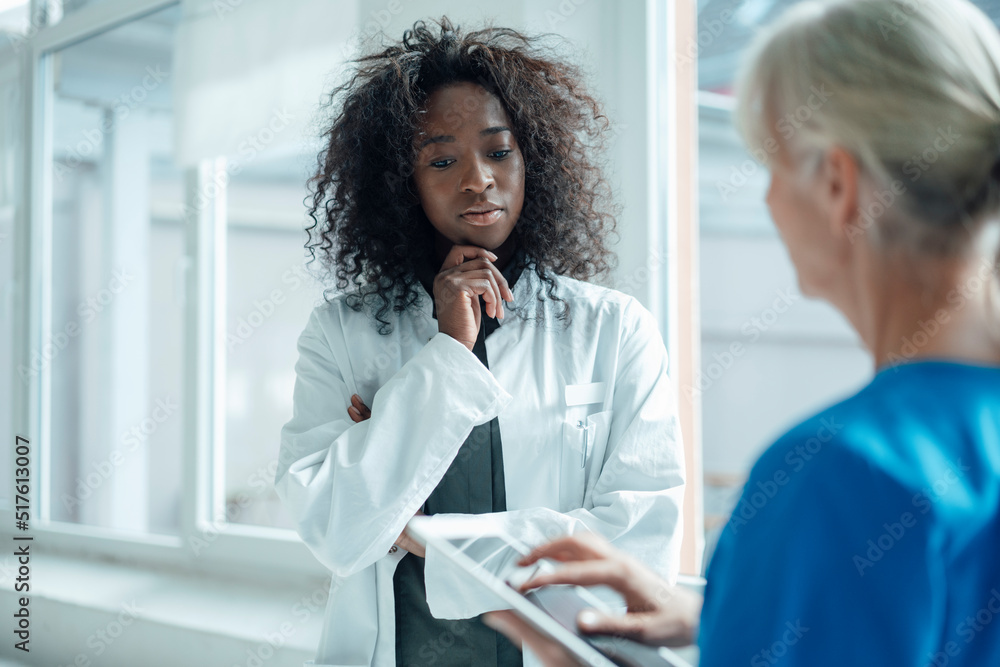 Nurse holding tablet PC talking with female doctor Nurse holding tablet PC talking with female doctor