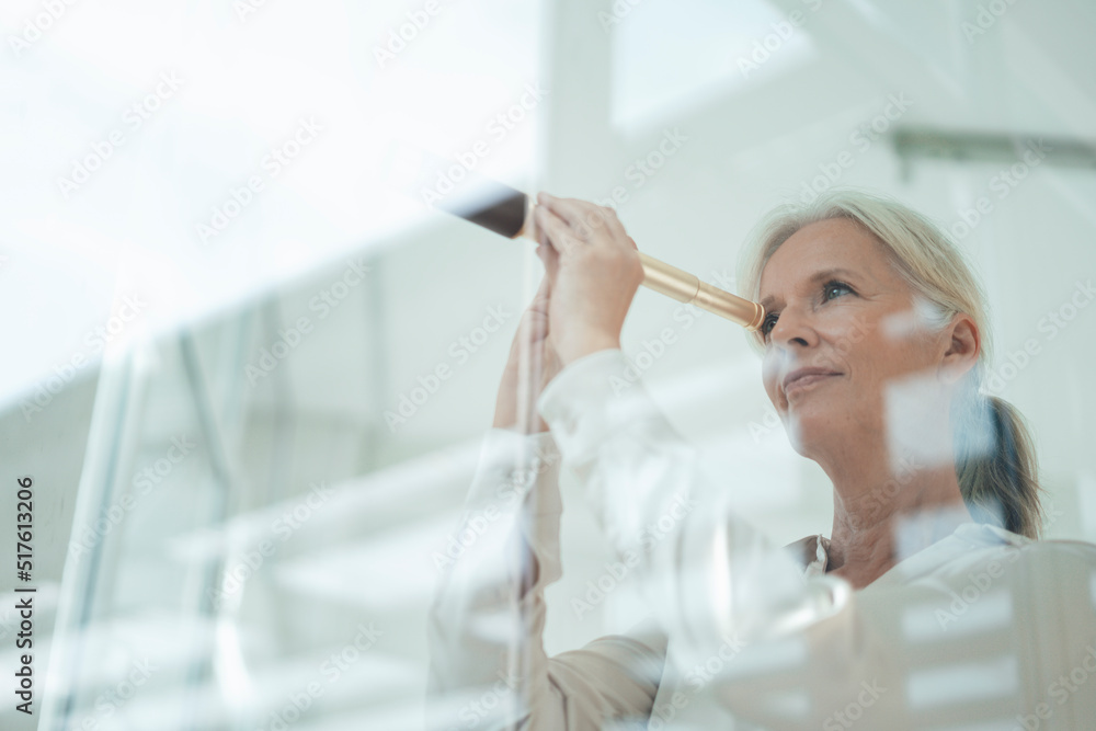 Smiling businesswoman looking through telescope Smiling businesswoman looking through telescope
