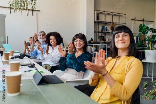 Smiling multiracial colleagues clapping hands in meeting at office photo