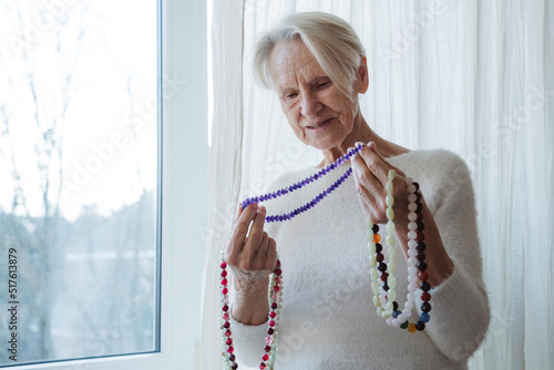 Happy senior woman holding gemstone beads necklace photo