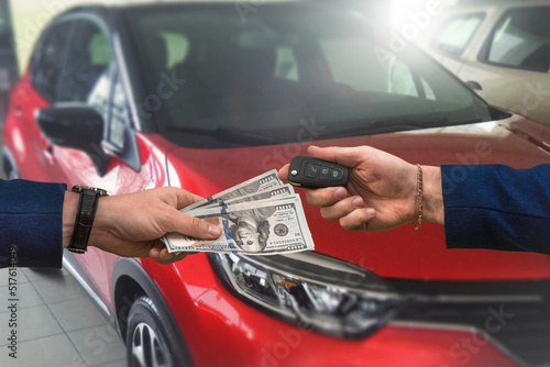 man hands over a large sum of dollars to another who in return passes the keys to a car bought © RomanR