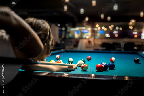 female player playing pool and aiming the billiard ball with cue photo