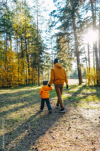 Father and son walking in autumn forest.