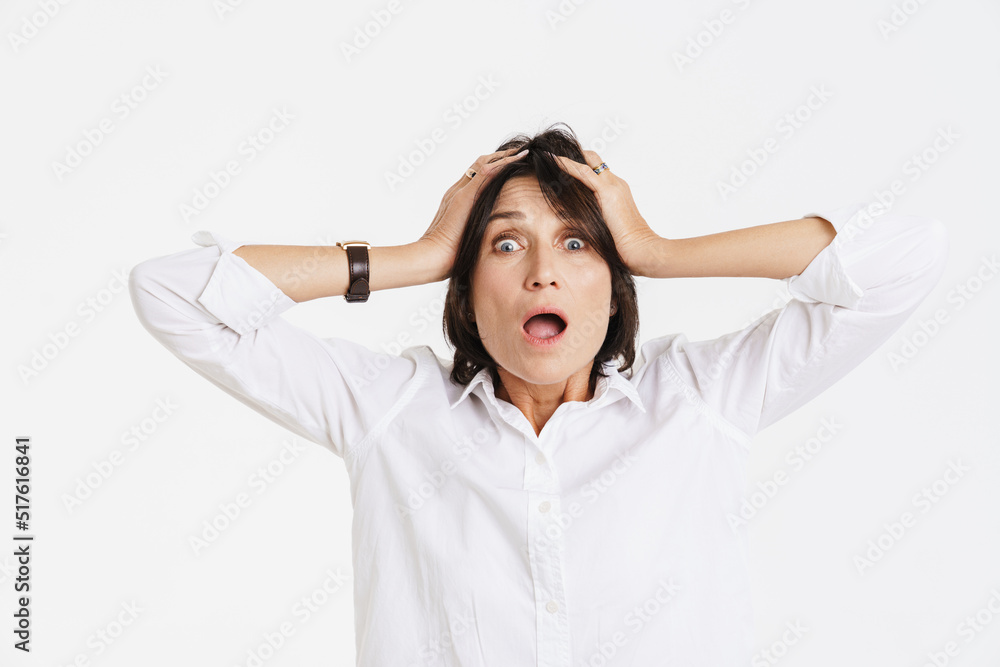 Mature brunette woman expressing surprise while holding her head Mature brunette woman expressing surprise while holding her head