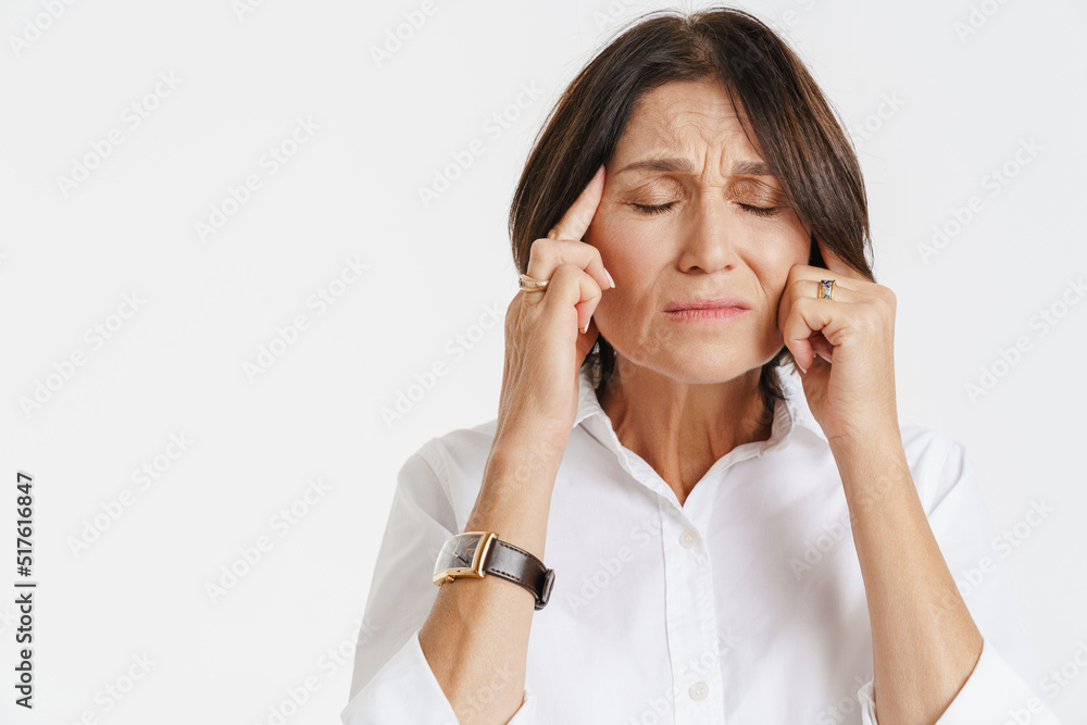 Mature woman with headache frowning while rubbing her temples Mature woman with headache frowning while rubbing her temples