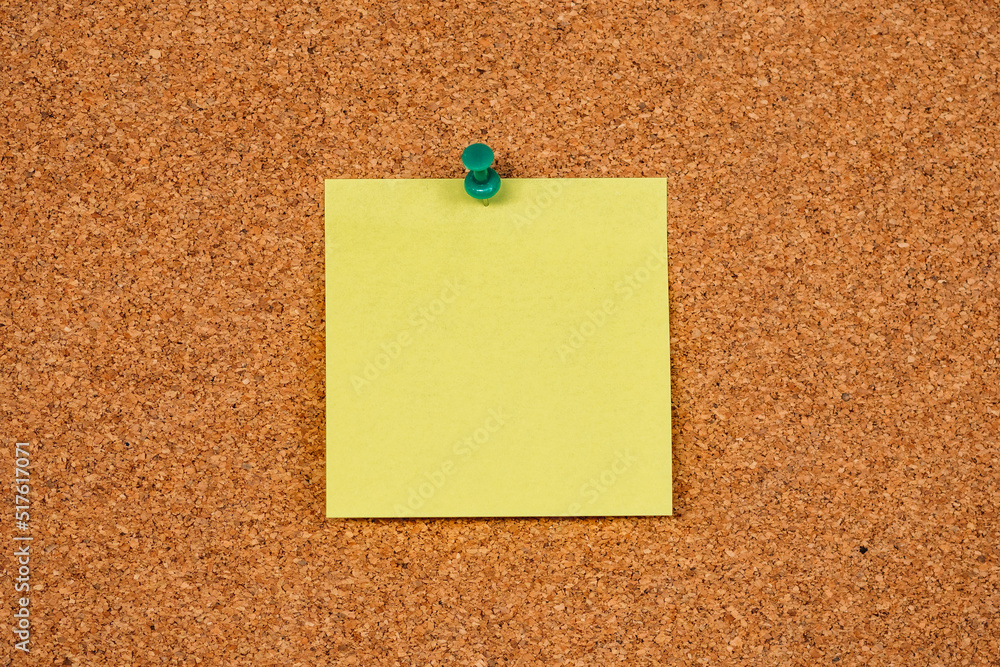Yellow sticky note pinned to a cork bulletin board with a green pushpin. Simple and clean background for reminders, messages, or announcements in an office or school setting Yellow sticky note pinned to a cork bulletin board with a green pushpin. Simple and clean background for reminders, messages, or announcements in an office or school setting