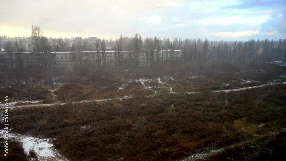 Winter weather outside the window. It is snowing and raining. Blizzard. Clouds and blue sky. Field and 5 storey house on the horizon. View from above. Snow Winter weather outside the window. It is snowing and raining. Blizzard. Clouds and blue sky. Field and 5 storey house on the horizon. View from above. Snow