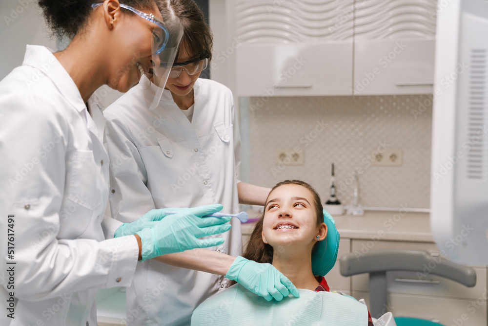Fototapeta premium Two multiracial dentists wearing lab coats working in dental clinic