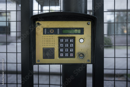 Intercom or door phone is electrical device allowing one-way or two-way communication. Retro golden colored intercom fixed on metal house gate.