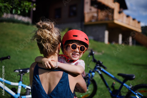 Young mother with little daughter preaparing for bike ride, putting on helmets and hugging. © Halfpoint