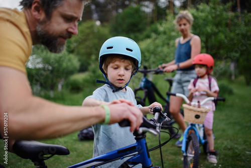 Portrait of young family with little children preapring for bike ride, standing with bicycles in nature. © Halfpoint