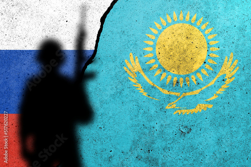 Russia and Kazakhstan flags painted on a concrete wall with soldier shadow. Relationship between Kazakhstan  and Russia photo