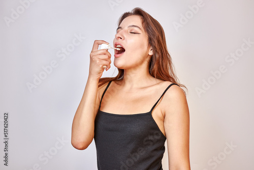 A beautiful girl sprays an aerosol on a sore throat.