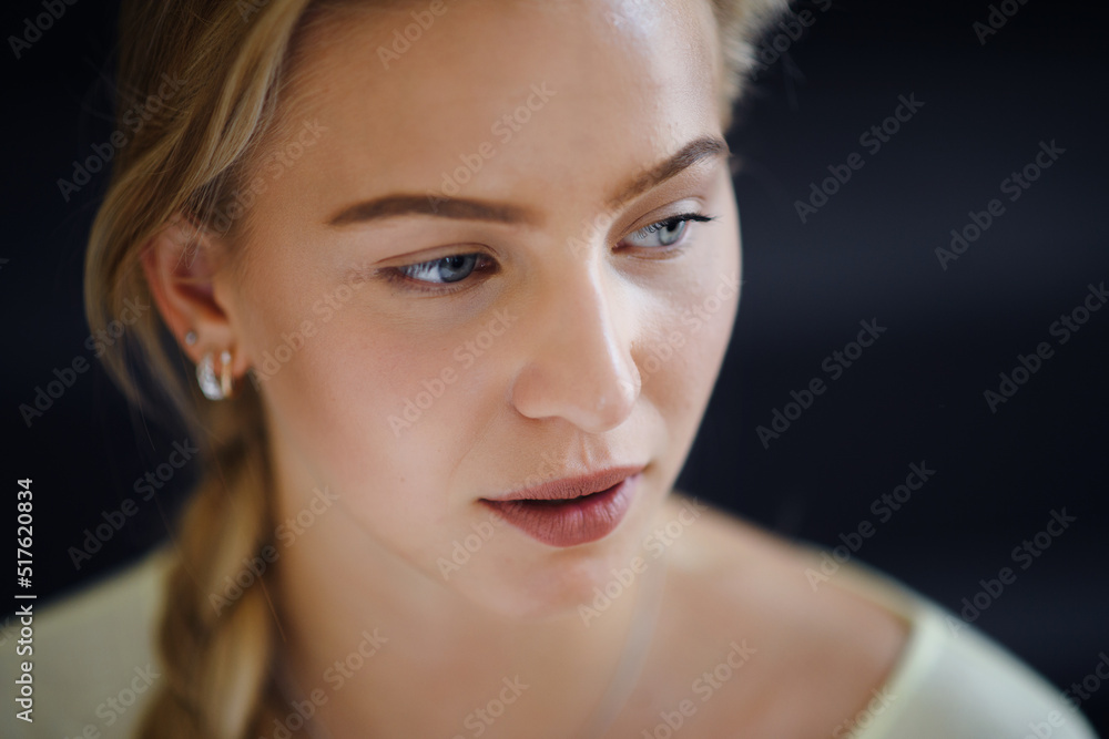 Portrait of beautiful blond young woman looking away and daydreaming on black background, close-up Portrait of beautiful blond young woman looking away and daydreaming on black background, close-up
