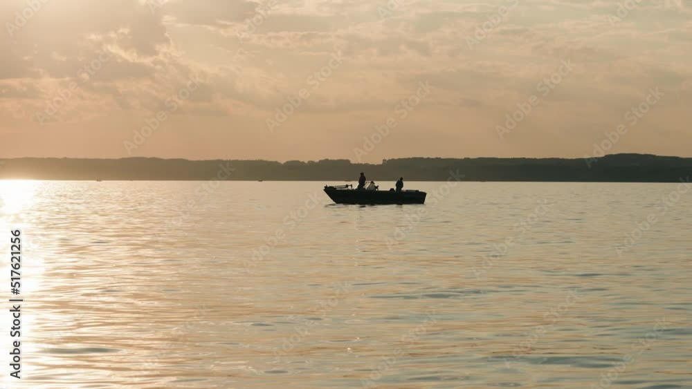 family fishing at sunset on a boat at the lake, back lit by the sun family fishing at sunset on a boat at the lake, back lit by the sun