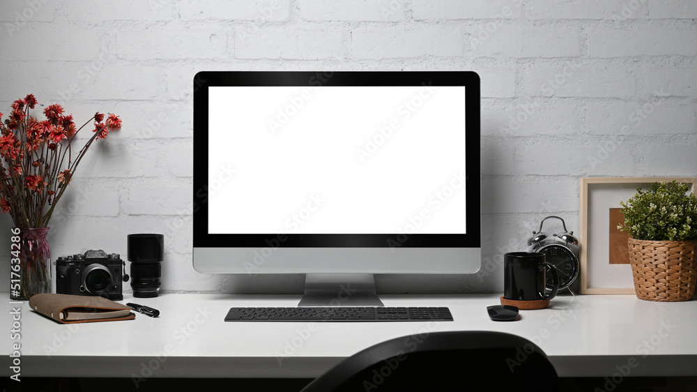 Fototapeta premium Creative workplace with computer pc, camera, notebook and houseplant on wooden desk. Empty display for your advertise text