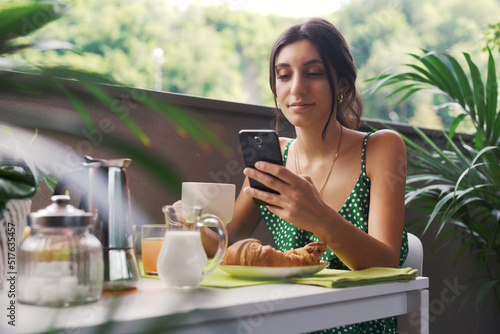 Woman having breakfast and using her phone
