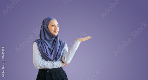 Portrait of a young muslim woman isolated on purple background, welcome or recommend concept. photo