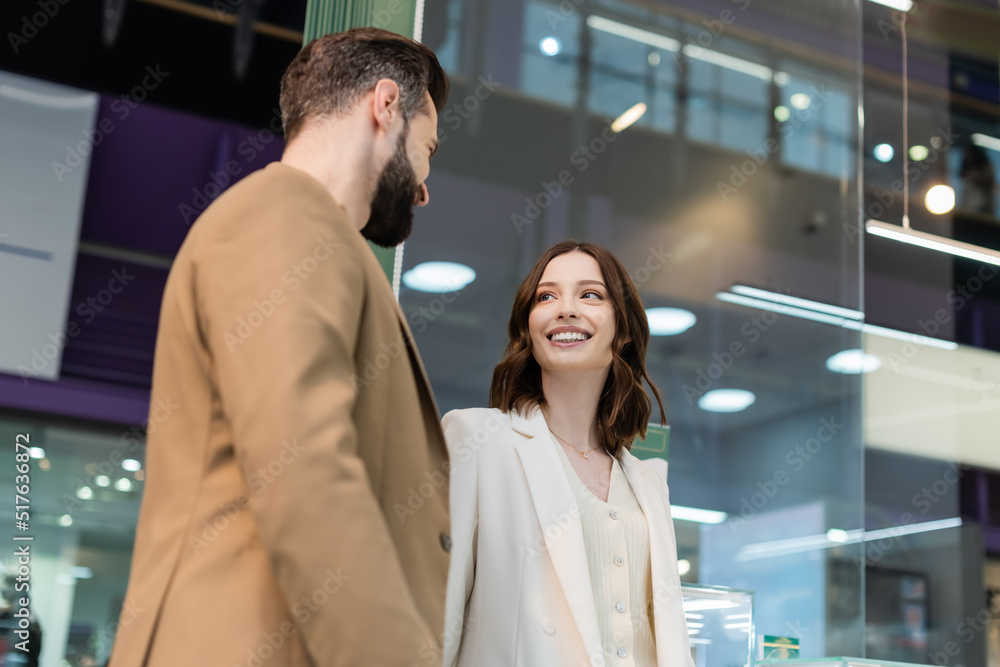 Low angle view of smiling young woman looking at boyfriend in jewelry shop. Low angle view of smiling young woman looking at boyfriend in jewelry shop.