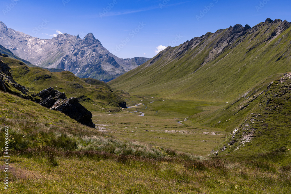 Aerial view towards the Capanna Motterascio, an alpine hut on the Greina plateau in Blenio, Swiss Alps. A rocky ridge on the right leads the eye towards the river that flows sinuously in the valley.