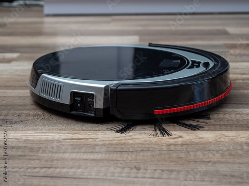 Robotic vacuum cleaner on a laminated wooden floor.