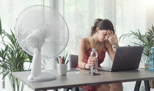 Woman cooling herself with an electric fan photo