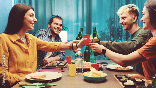 Happy friends toasting and eating together at home