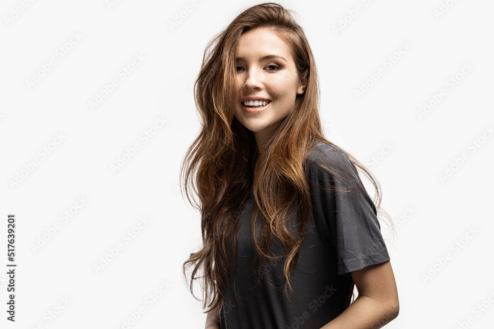 Portrait of carefree young smiling girl feeling happy indoors. Cheerful woman in good mood posing in studio on white background. Happiness and positivity concept
