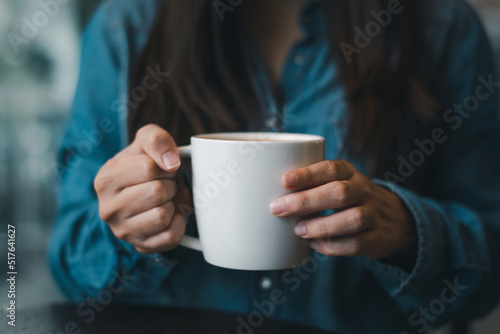 Woman in blue t-shirt holding big white coffee cup.Mock up of clean coffee cup, sweet coffee or tea..