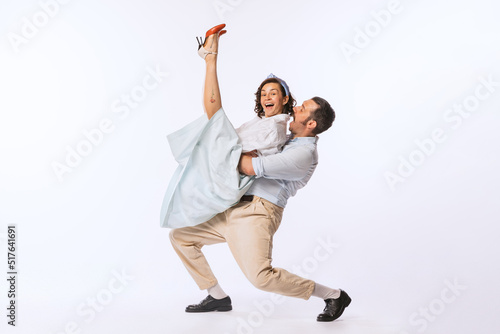 Portrait of beautiful couple, man and woman, dancing over white studio background. Recreation of dance styles.