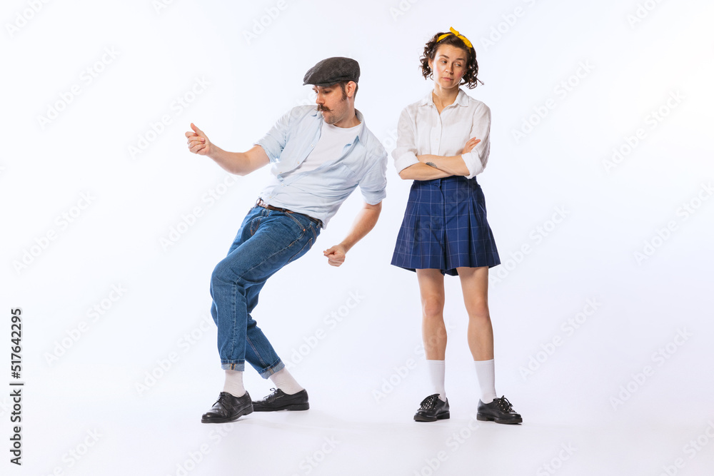 Portrait of young stylish woman and dancing cheerful man posing isolated over white studio background