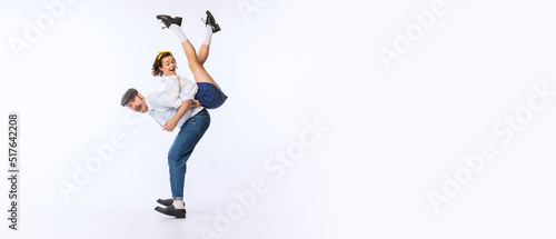 Portrait of young cheerful couple, man and woman, in stylish retro outfit dancing isolated over white studio background. FLyer © Lustre