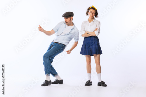 Portrait of young stylish woman and dancing cheerful man posing isolated over white studio background