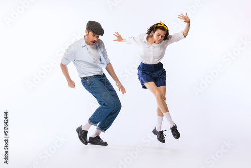 Portrait of young beautiful couple, man and woman, dancing boogie woogie isolated over white studio background photo