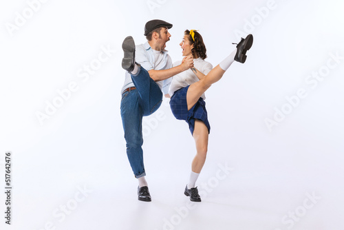 Portrait of young emotive couple, man and woman, dancing boogie woogie isolated over white studio background. Excitement