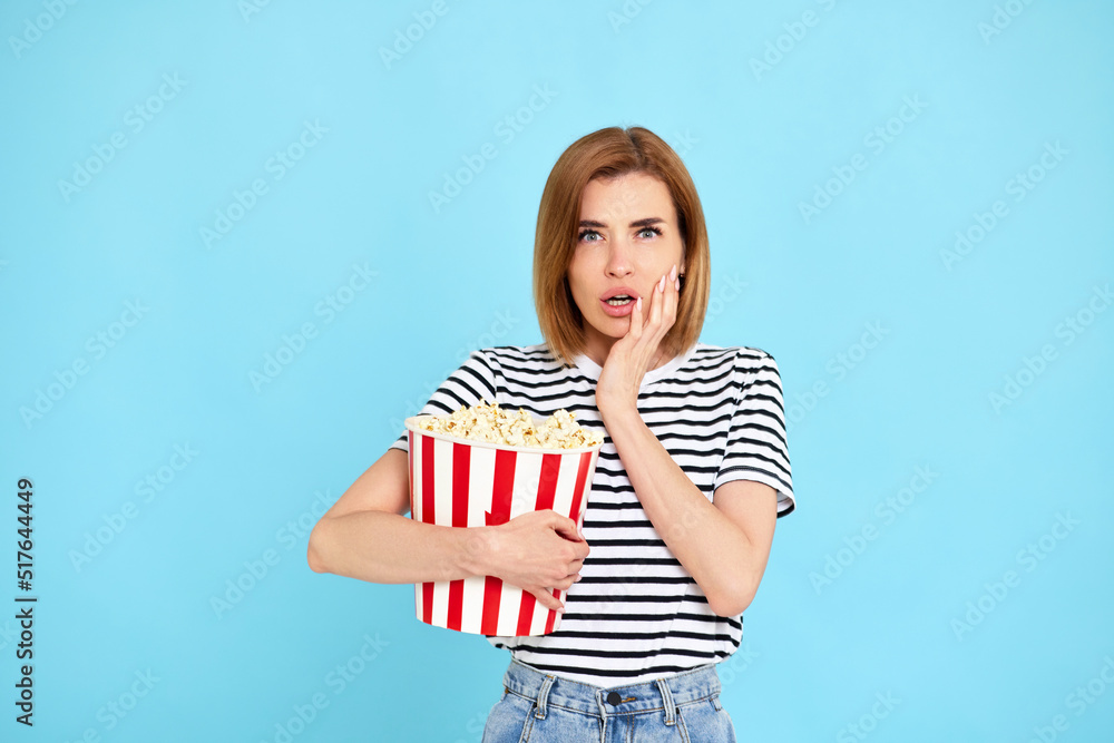 woman watching movie film, holding bucket of popcorn woman watching movie film, holding bucket of popcorn